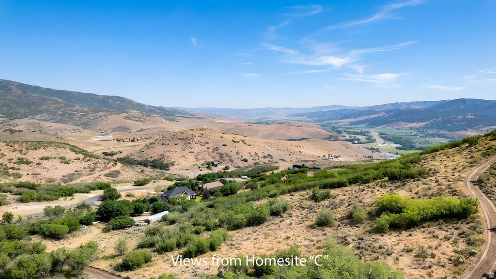 Expansive valley panorama featuring distant mountain ranges and scattered residential structures