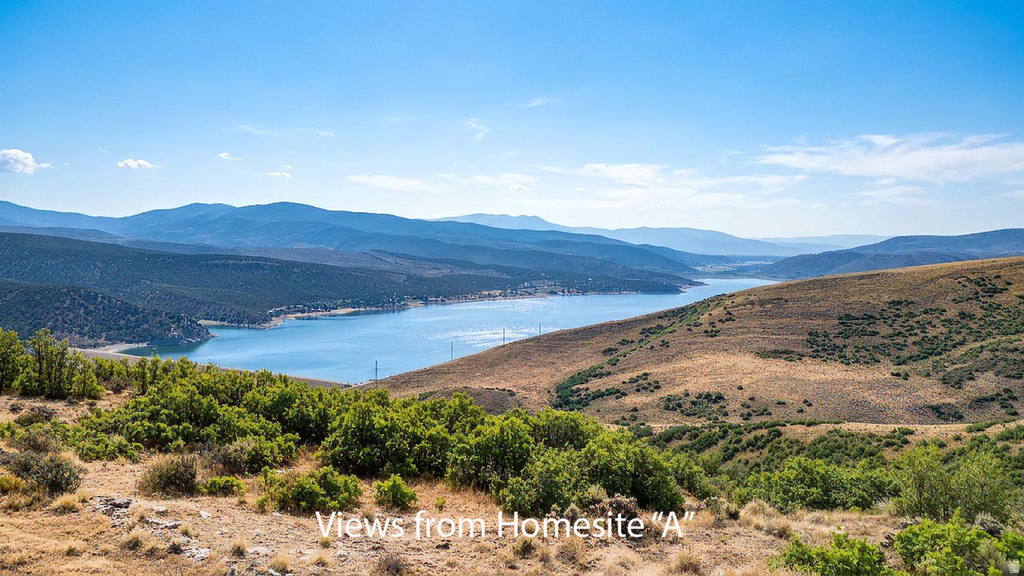 Expansive landscape featuring distant mountains, a large body of water, and natural brush