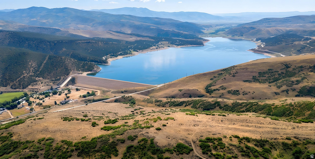 Expansive aerial landscape featuring a large blue reservoir surrounded by rolling hills and distant mountains