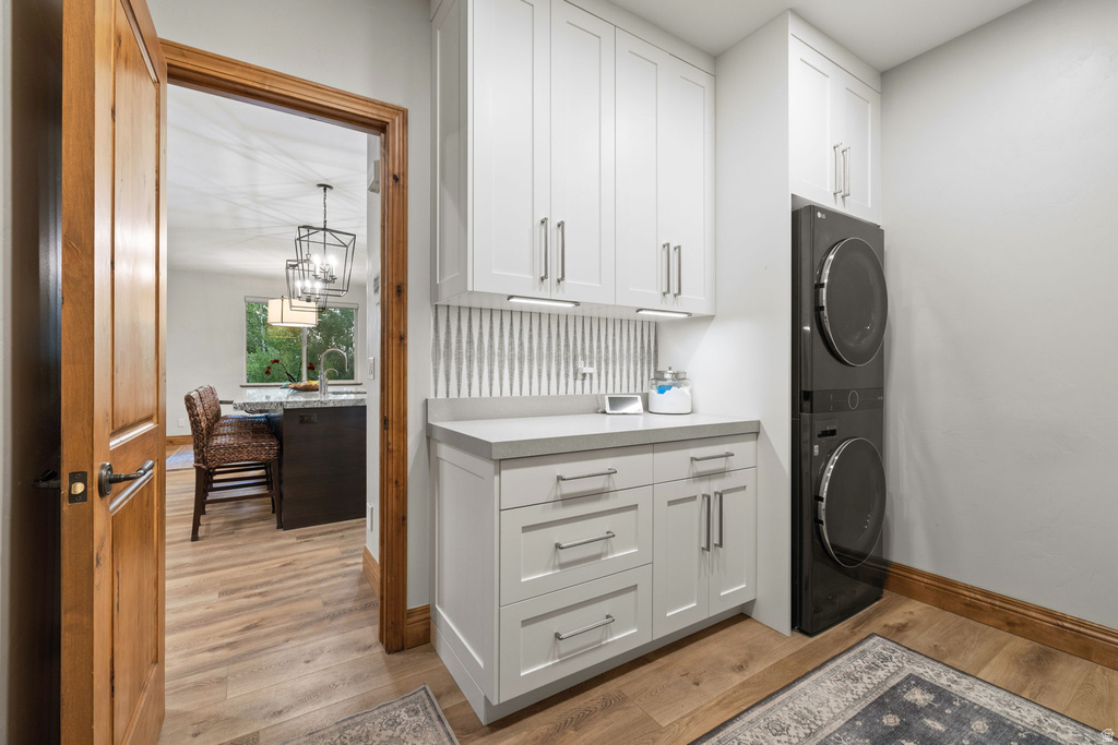 Dedicated utility area featuring a stacked washer and dryer, white shaker cabinetry, a light gray countertop, and a textured vertical backsplash