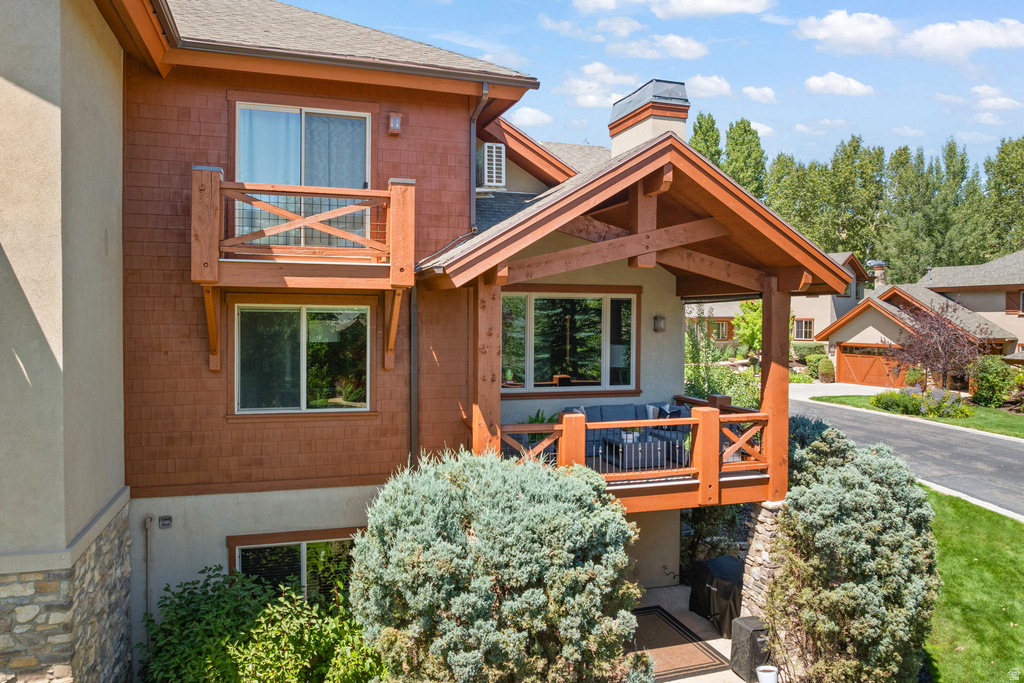 Multi-level exterior featuring wood shingle siding, a covered porch with exposed timber framing, a private balcony, and stone accents
