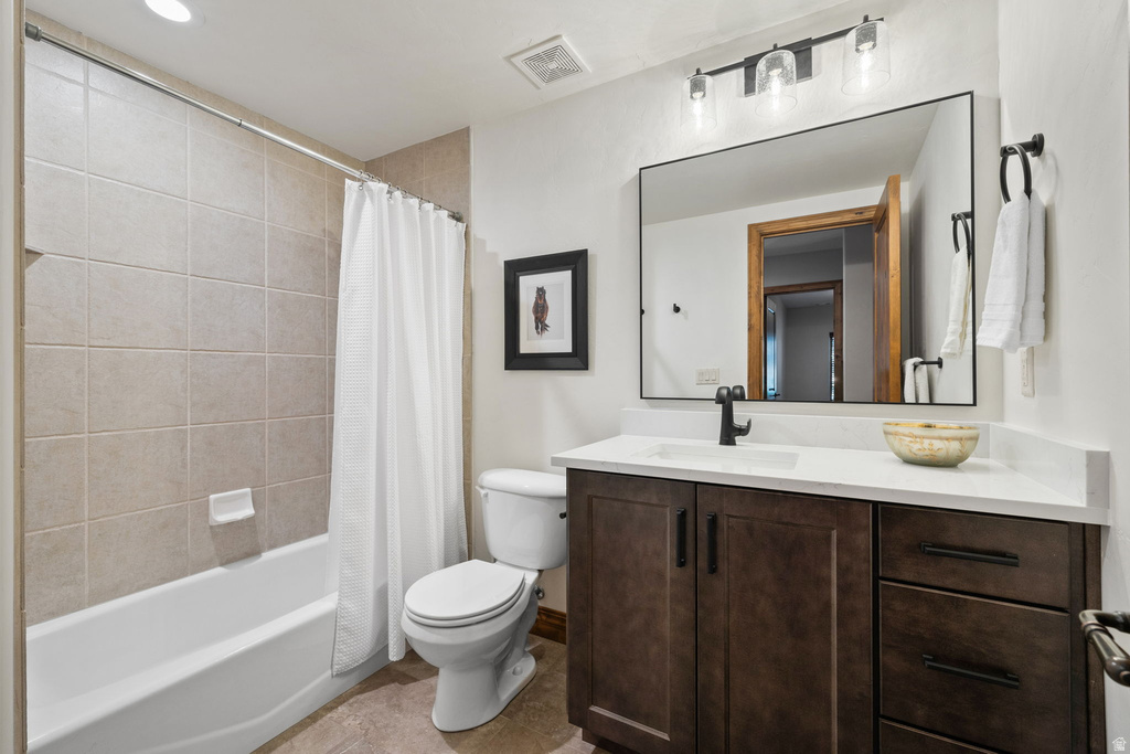 Bathroom featuring a tub and shower combination with light-toned tile surround, a dark wood-finish vanity with a white countertop and integrated sink, a rectangular mirror, and a three-light vanity fixture