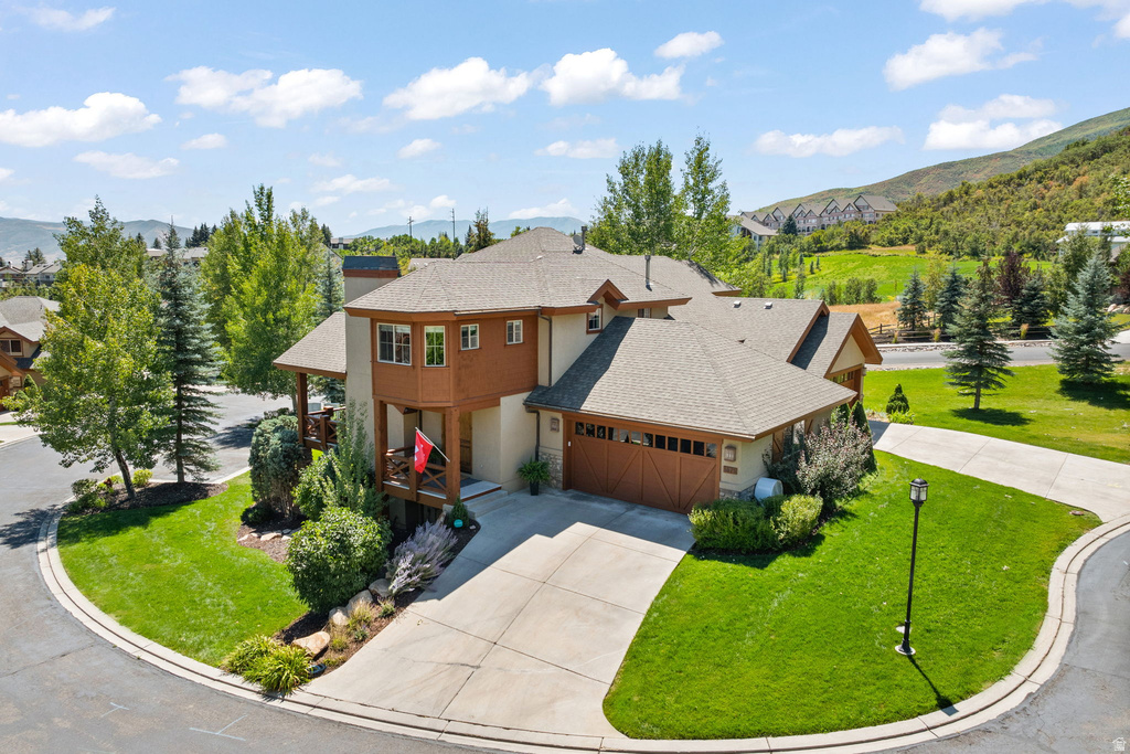 Contemporary residence featuring a multi-level design, attached two-car garage with wood-panel doors, and a covered balcony