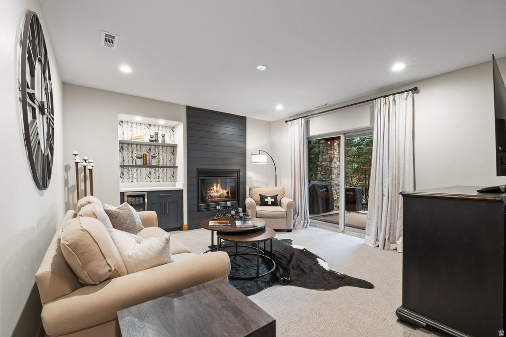 Living area featuring a fireplace with shiplap-style surround, built-in shelving, a beverage cooler, and sliding glass doors