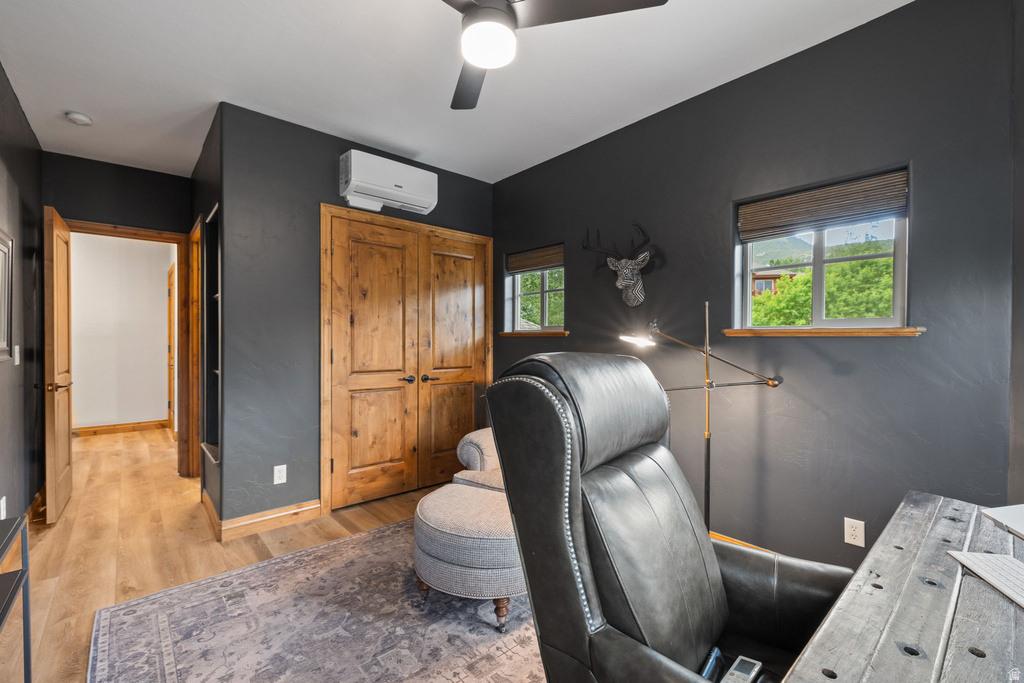 Interior space featuring dark accent walls, wood-finish flooring, two natural wood double doors, and a ceiling fan with integrated lighting