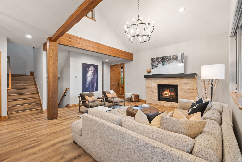 Living area featuring vaulted ceilings with exposed wood beams, a stone fireplace with a dark wood mantel, and wood-finish flooring