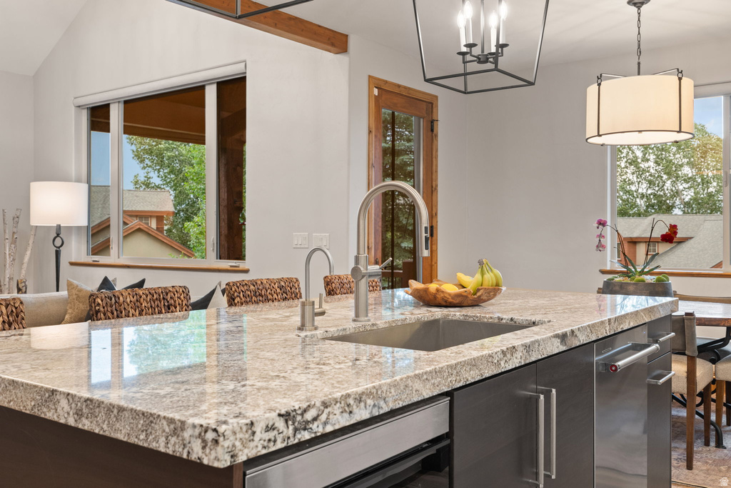 Kitchen island featuring a stainless steel sink, a pull-down faucet, and a light-toned patterned countertop