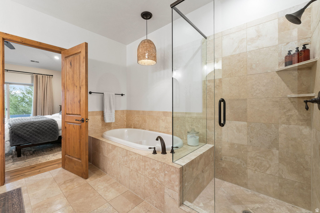 Tile-surround soaking tub with bronze fixtures, glass-enclosed shower with tiled walls and built-in shelving, wood-paneled door, and recessed lighting
