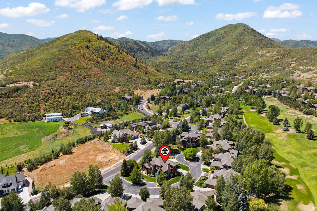 Residential community situated among verdant hills, featuring mature trees and a manicured golf course