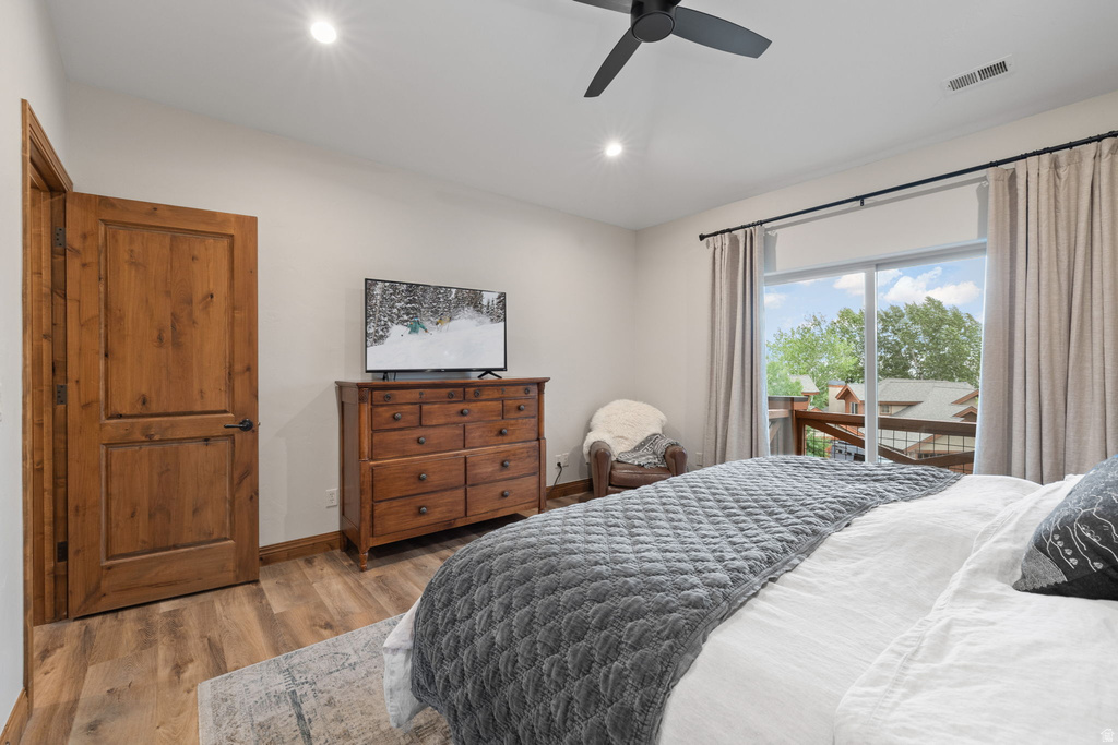 Bedroom featuring wood-finish flooring, a wood-paneled door, recessed lighting, and a ceiling fan