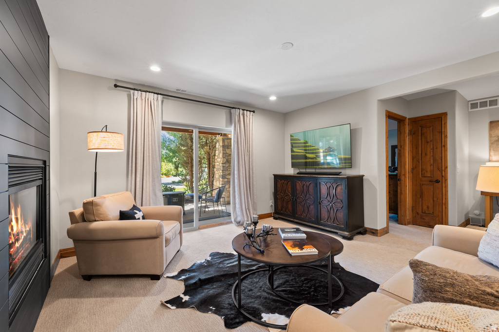 Living area featuring a fireplace with shiplap-style surround, recessed lighting, and sliding glass door access to an outdoor patio