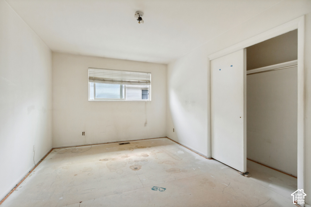 Room featuring a window with horizontal blinds, a ceiling-mounted light fixture, and a built-in closet with sliding doors