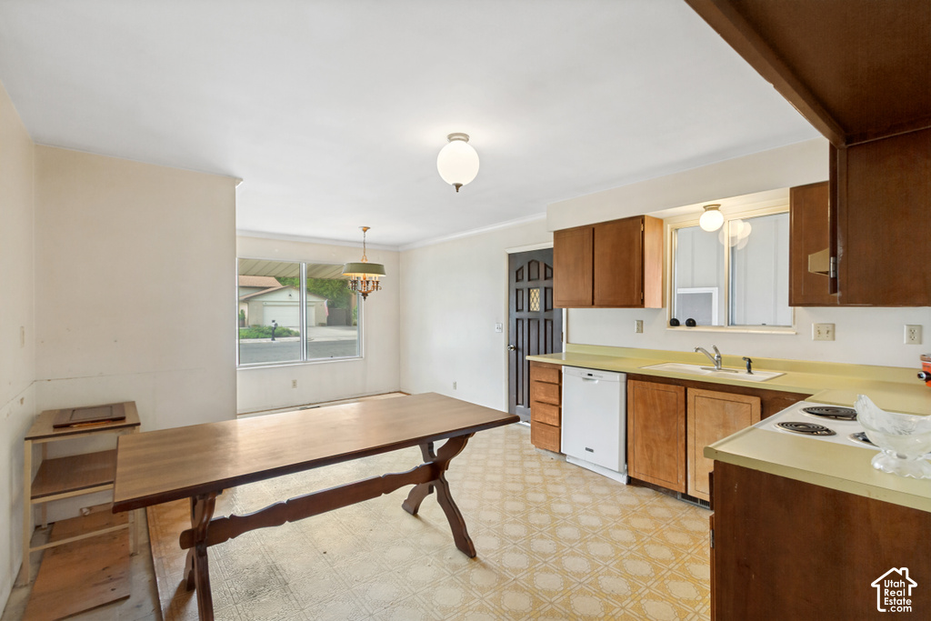 Kitchen and dining area featuring wood-finish cabinetry, a white dishwasher, a built-in range, a stainless steel sink, and patterned flooring