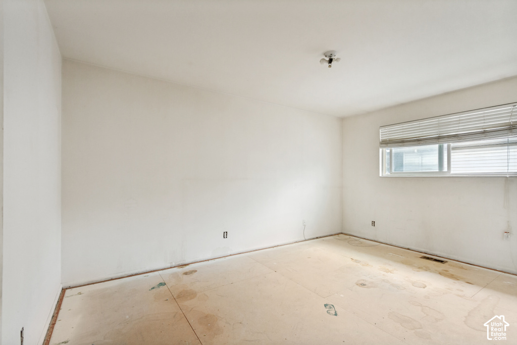 Spacious room featuring neutral painted walls, a window with horizontal blinds, and a flush-mount ceiling light fixture