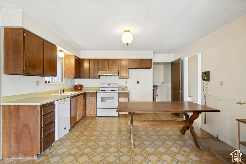 Kitchen featuring wood-finish cabinetry, light-toned countertops, and a full suite of white appliances including a dishwasher and range