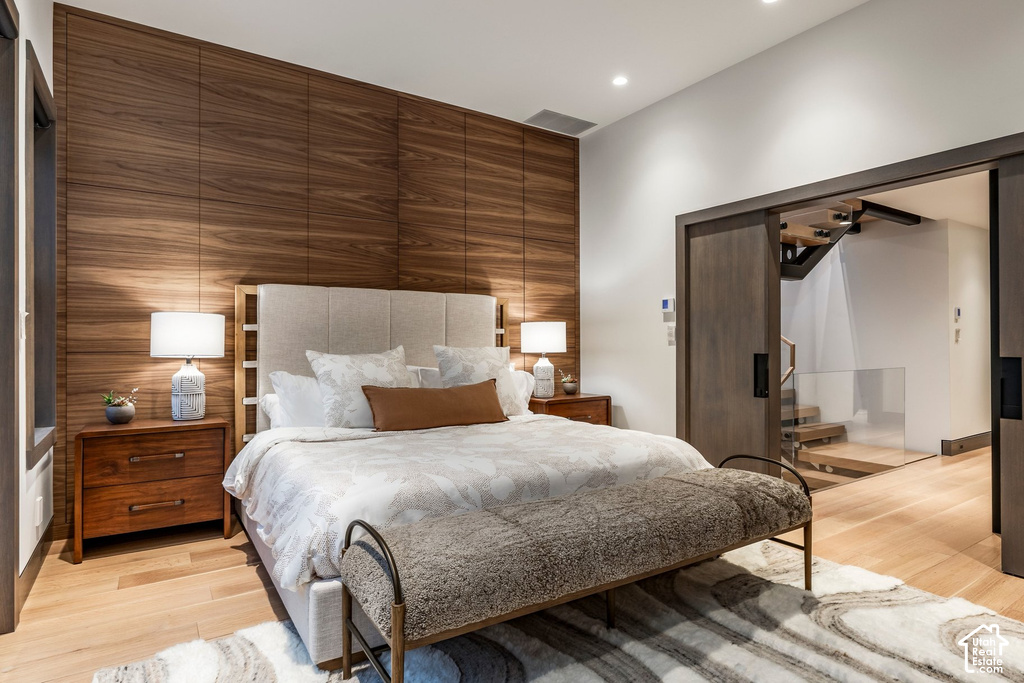 Bedroom featuring a wood-panel accent wall and light wood-finish flooring