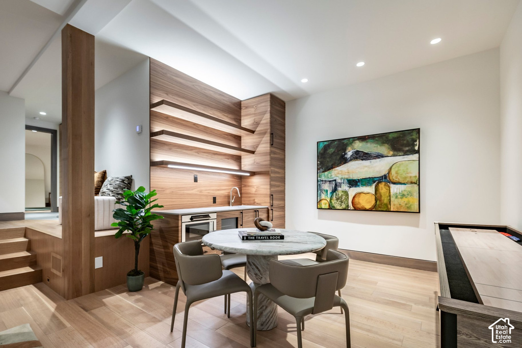 Integrated wet bar featuring wood-finish cabinetry, under-cabinet lighting, and a built-in microwave