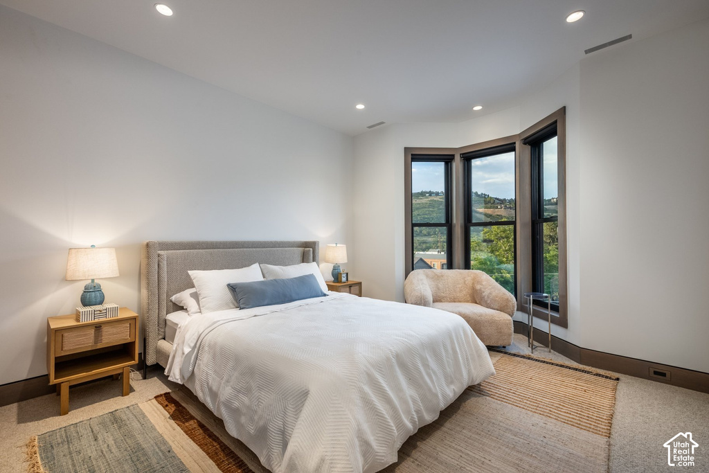Recessed lighting illuminates this room, featuring a bay window with dark trim and a substantial window seat area