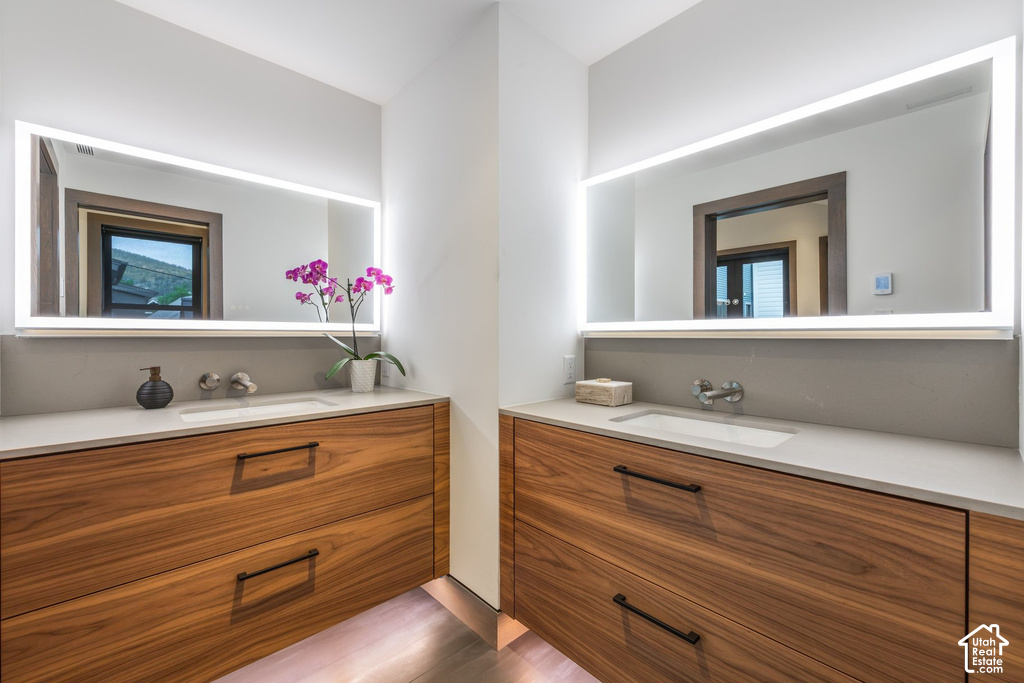 Dual vanity featuring wood-finish cabinetry, integrated sinks, and light-toned countertops