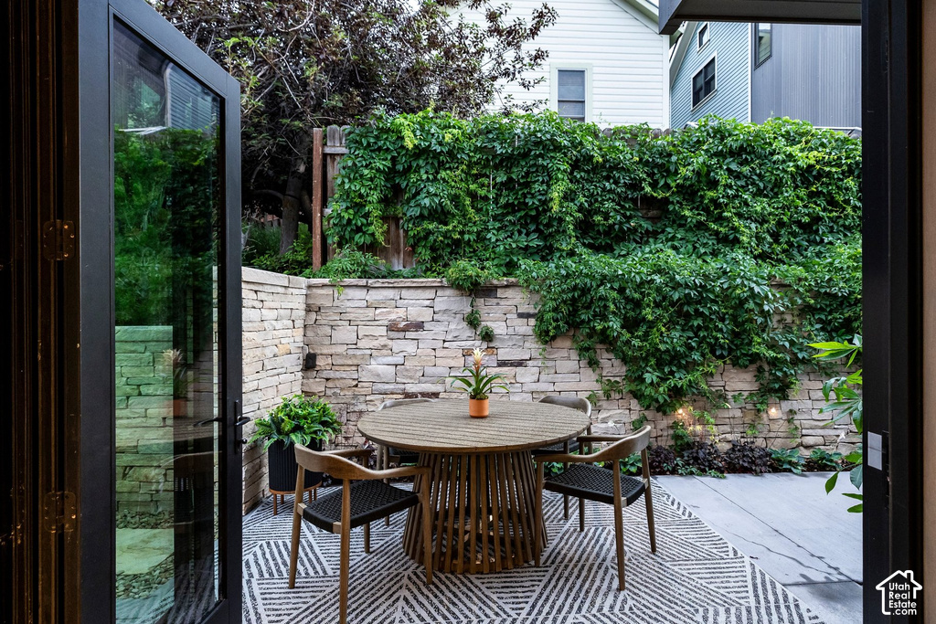 Outdoor patio featuring a stone retaining wall with integrated lighting, lush green climbing foliage, and bi-fold glass doors