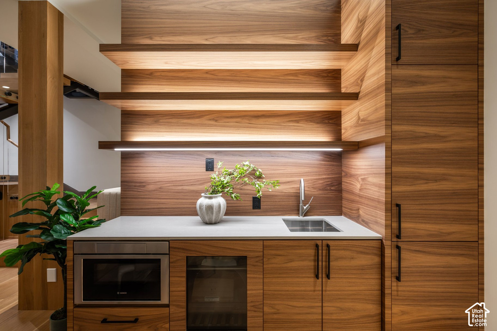 Integrated wet bar featuring wood-finish cabinetry, a single basin sink, and a stone-finish countertop