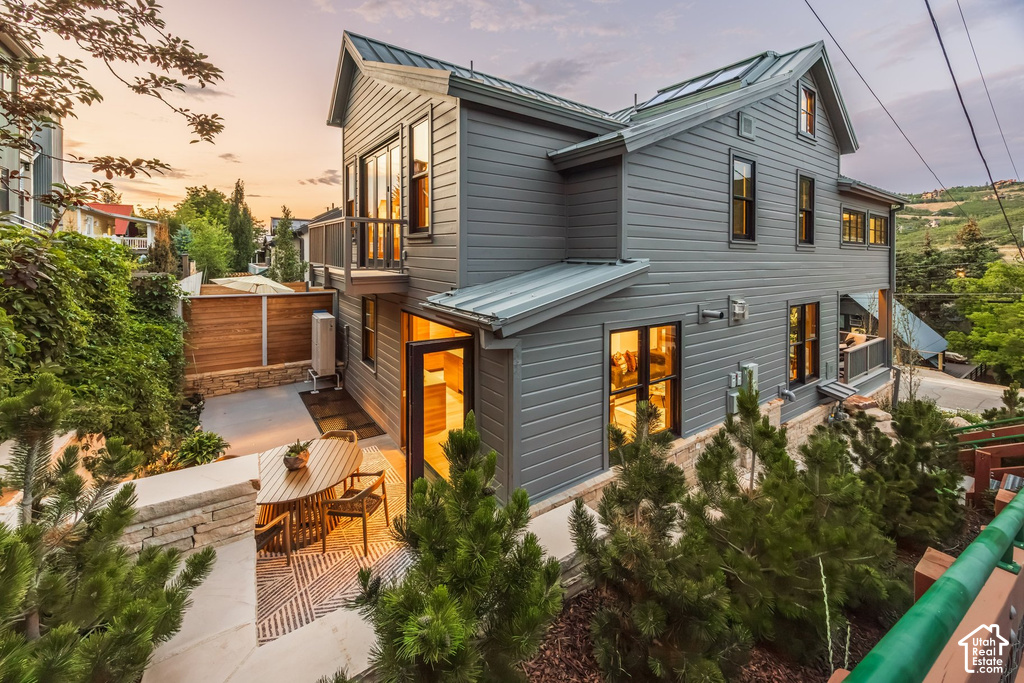 Contemporary residence featuring gray siding, a metal roof, and multiple windows with dark frames