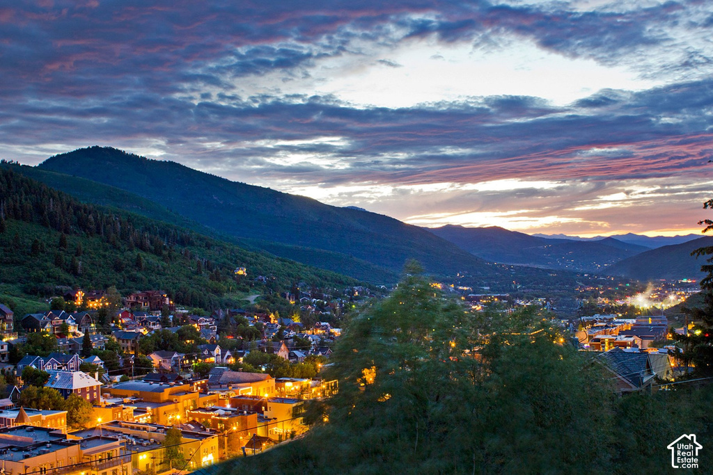 Mountainous landscape featuring a town with illuminated buildings and a colorful sky