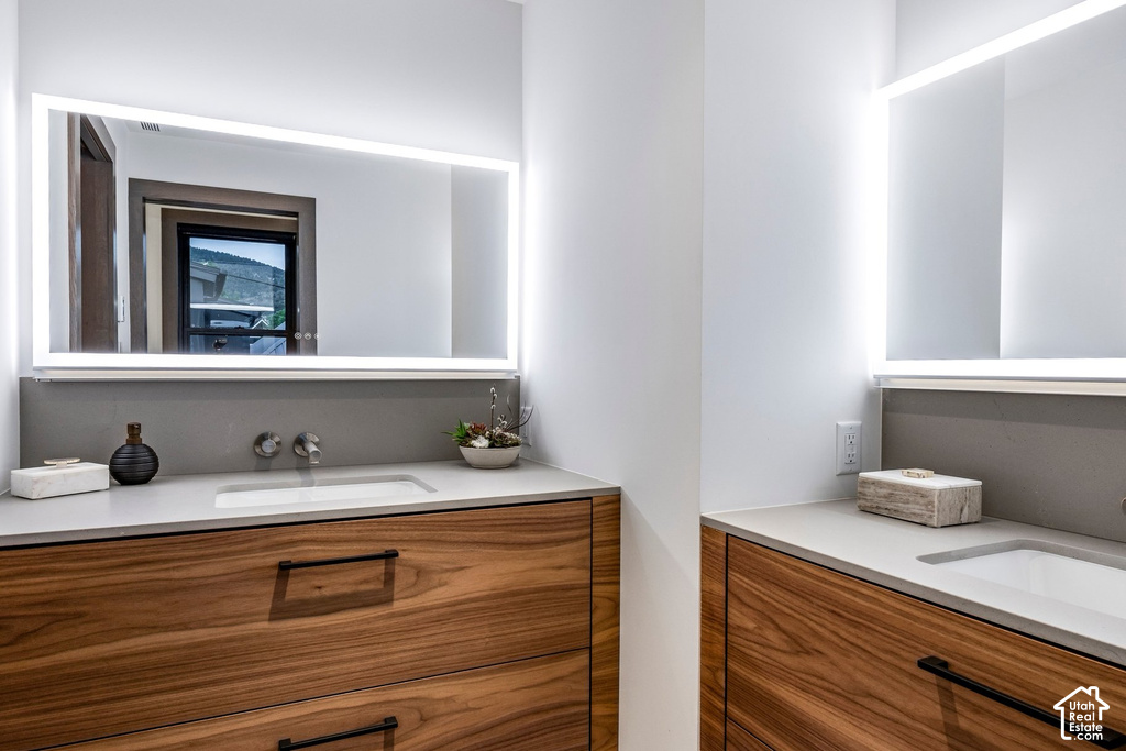 Modern bathroom vanity featuring wood-finish cabinetry, integrated sinks, light-colored countertops, and wall-mounted faucets
