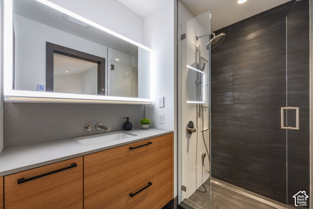 Bathroom featuring a wood-finish vanity with dark hardware, an undermount sink, and a light-toned countertop