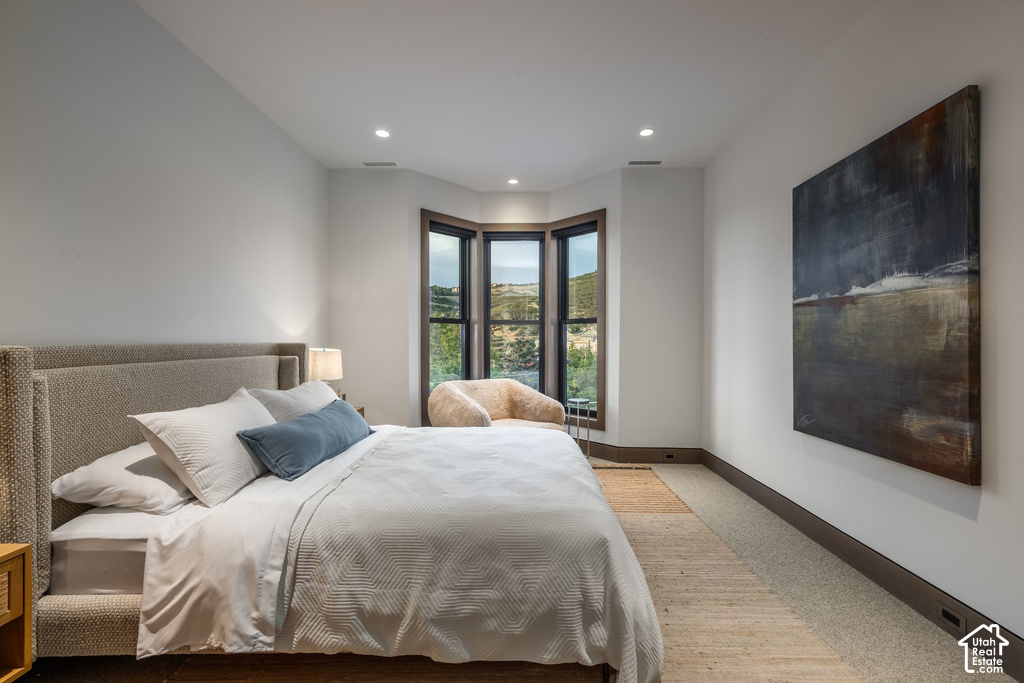 Bay window with dark trim framing distant mountain scenery, recessed ceiling lighting, and light-colored carpeting