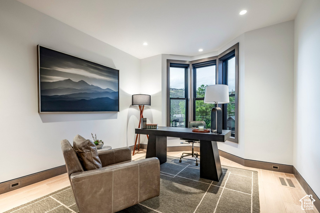 Room featuring a bay window, light wood-finish flooring, recessed lighting, and dark wood trim