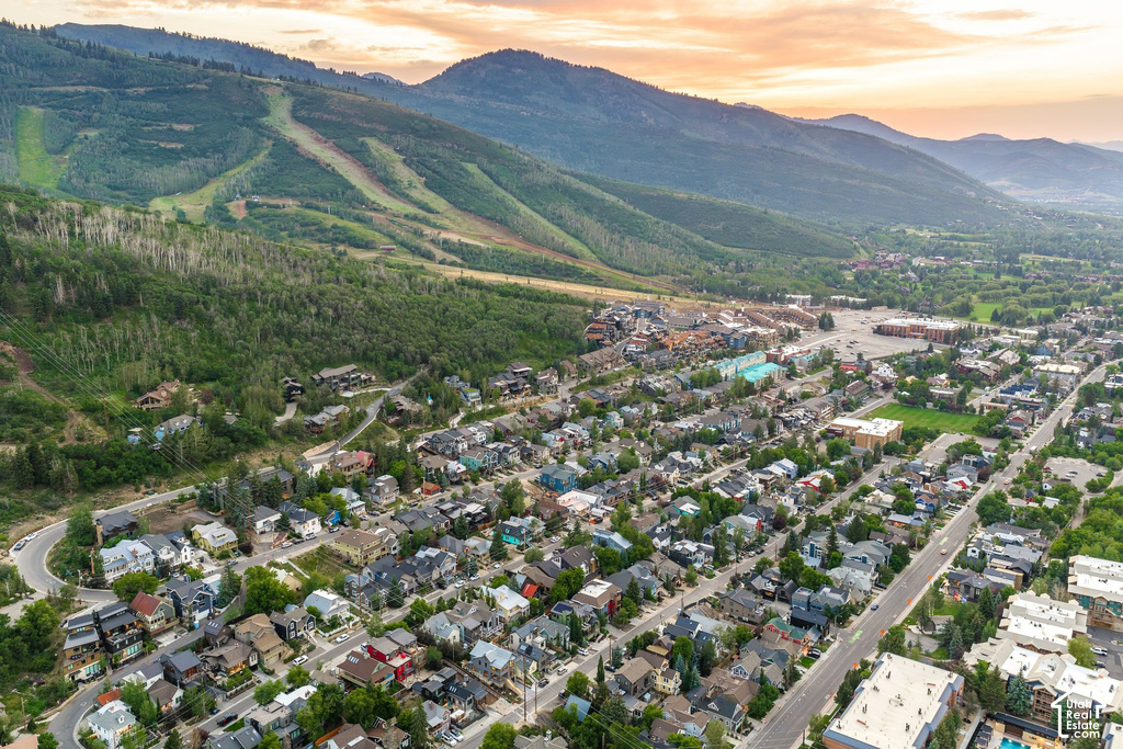 Expansive aerial perspective showcasing a residential community nestled at the base of a verdant, mountainous landscape with visible ski slopes