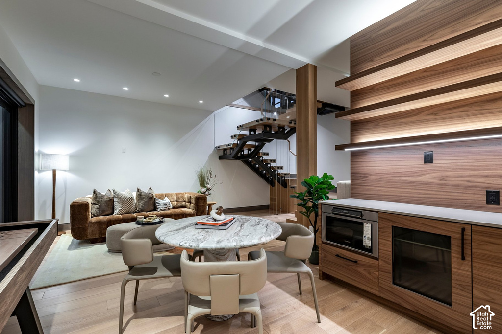 Integrated entertaining space featuring a built-in wet bar with wood-finish cabinetry, stainless steel microwave, and beverage cooler