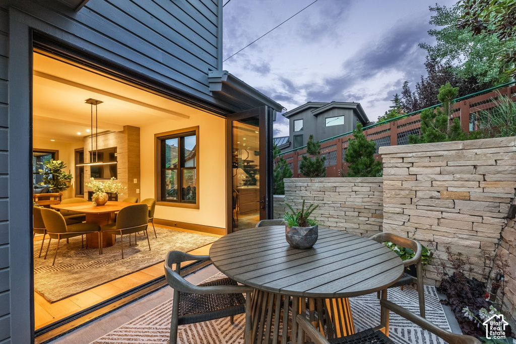Outdoor patio featuring a stone wall, wood-finish slatted table, and a geometric-patterned outdoor rug