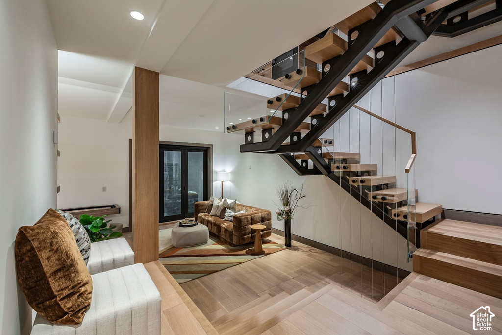Floating staircase with wood treads, black metal stringers, and glass panel railing