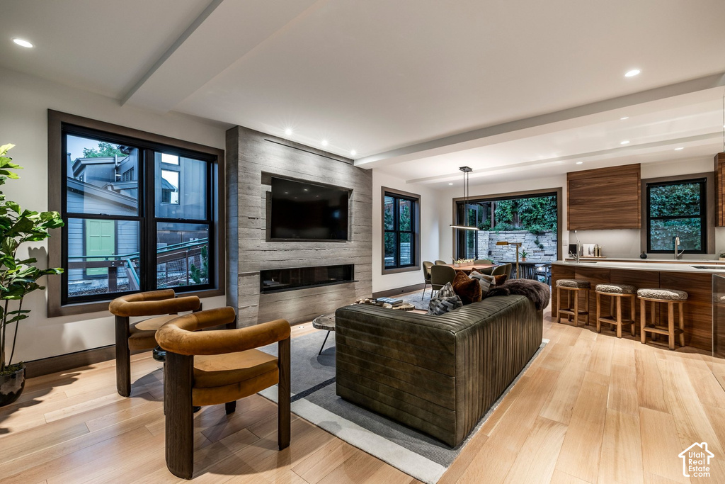 Open-concept living area with light wood-finish flooring, recessed lighting, and a linear fireplace