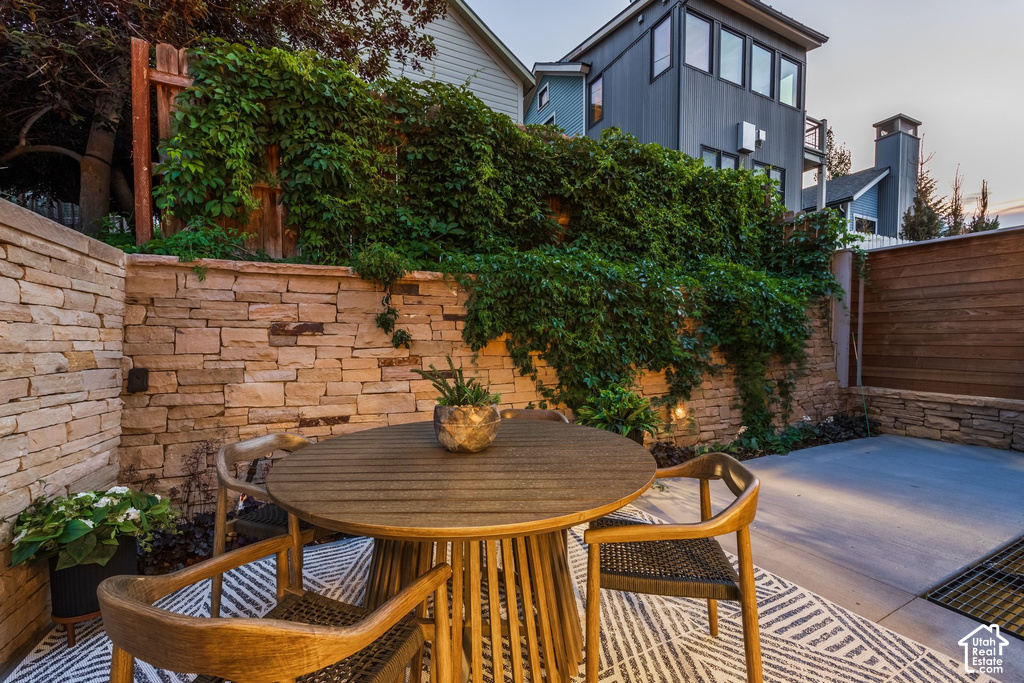 Outdoor patio area featuring stacked stone retaining walls, integrated lighting, and a slatted wood privacy fence