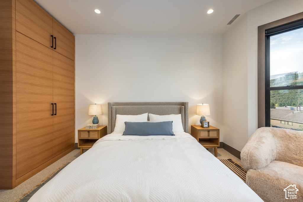 Bedroom featuring a built-in wood-finish wardrobe with black hardware, recessed ceiling lighting, and a window with dark trim