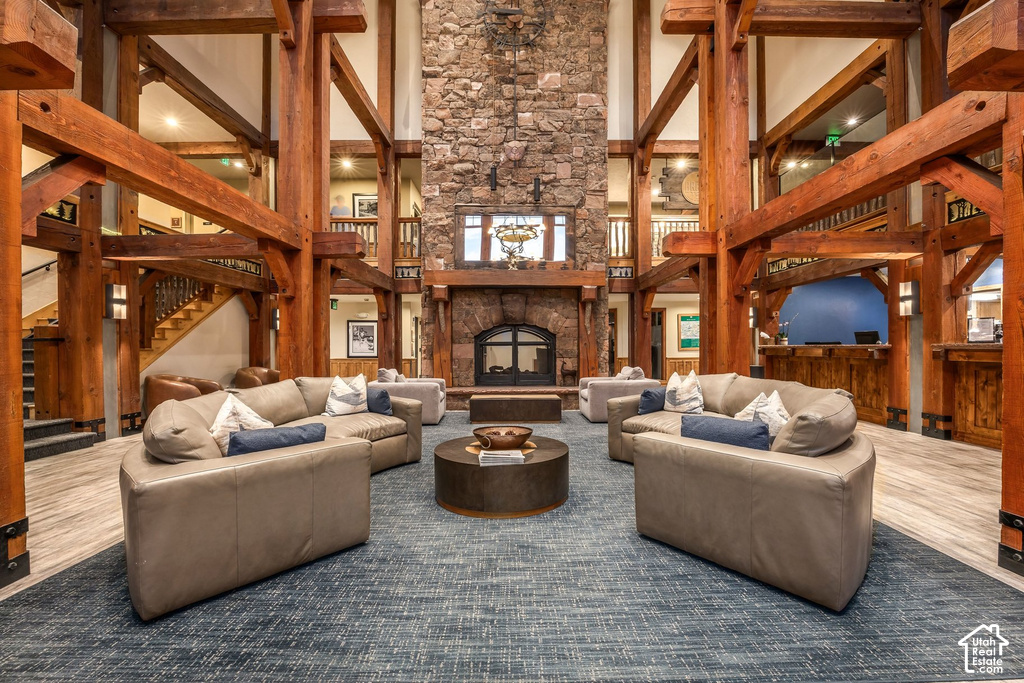 Spacious common area featuring exposed timber framing, a stone fireplace, and a large area rug