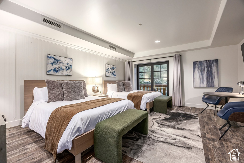 Bedroom featuring two beds, wood-finish flooring, and a private balcony access through double doors