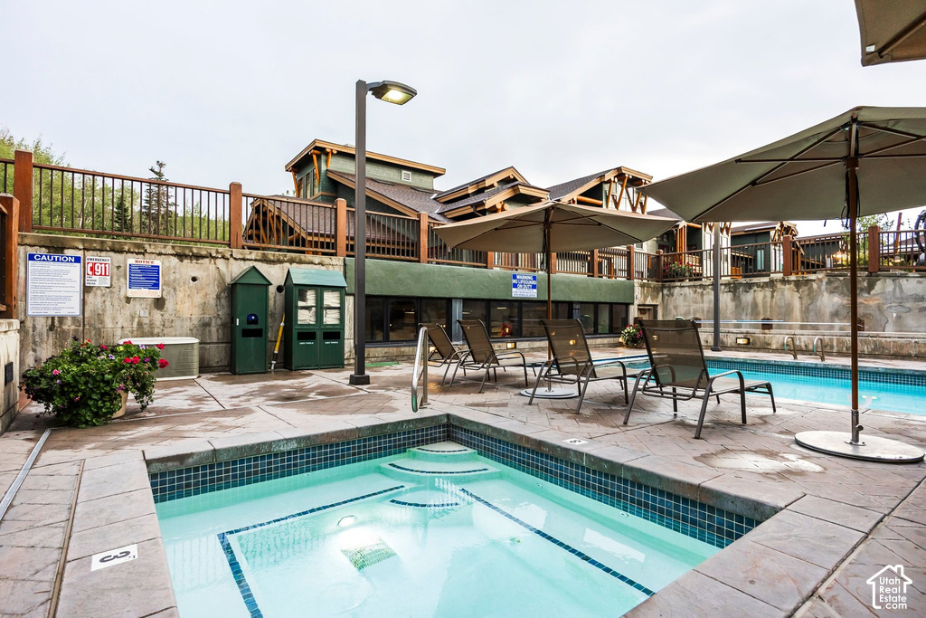 Outdoor spa with blue mosaic tile and stone coping