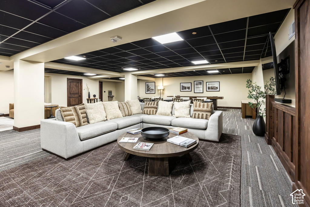 Spacious common area featuring a sectional sofa, a round wood coffee table, and patterned carpet flooring