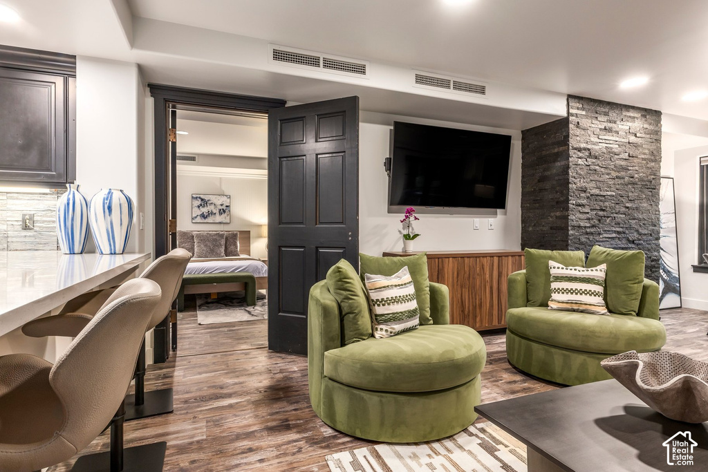 Lounge area featuring wood-finish flooring, a stacked stone accent wall, and recessed lighting