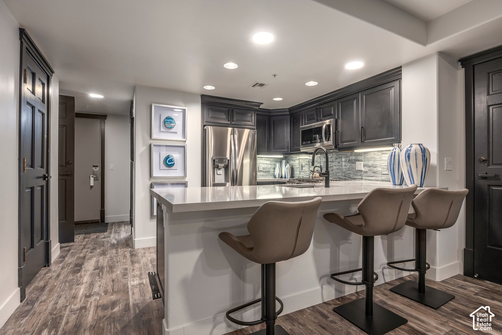 Kitchen featuring dark cabinetry, stainless steel appliances, and a light-toned countertop