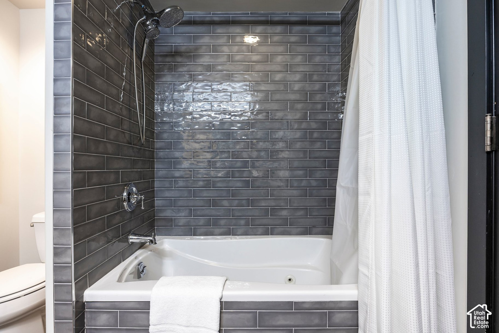Soaking tub with jetted features surrounded by dark gray subway tile