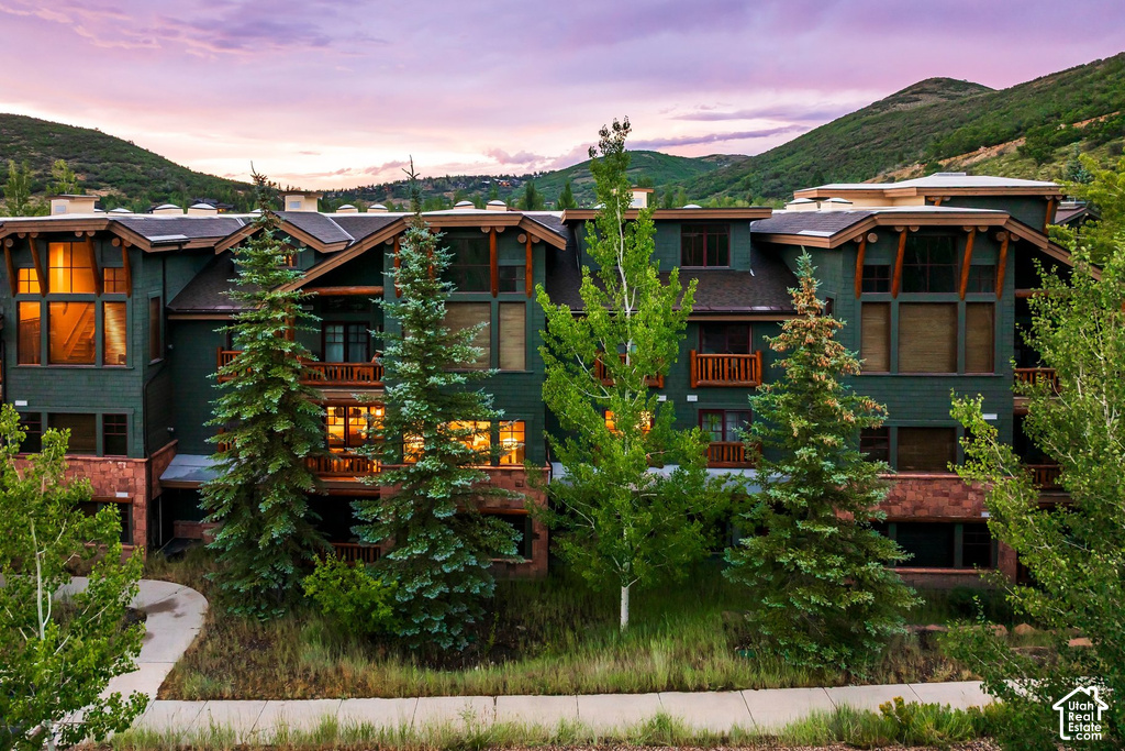 Multi-story structure featuring dark green siding, stone accents, and wood detailing