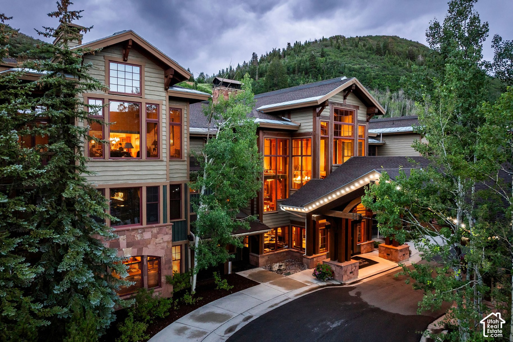 Exterior featuring multiple gables, extensive window placement, natural wood siding, and stone accents