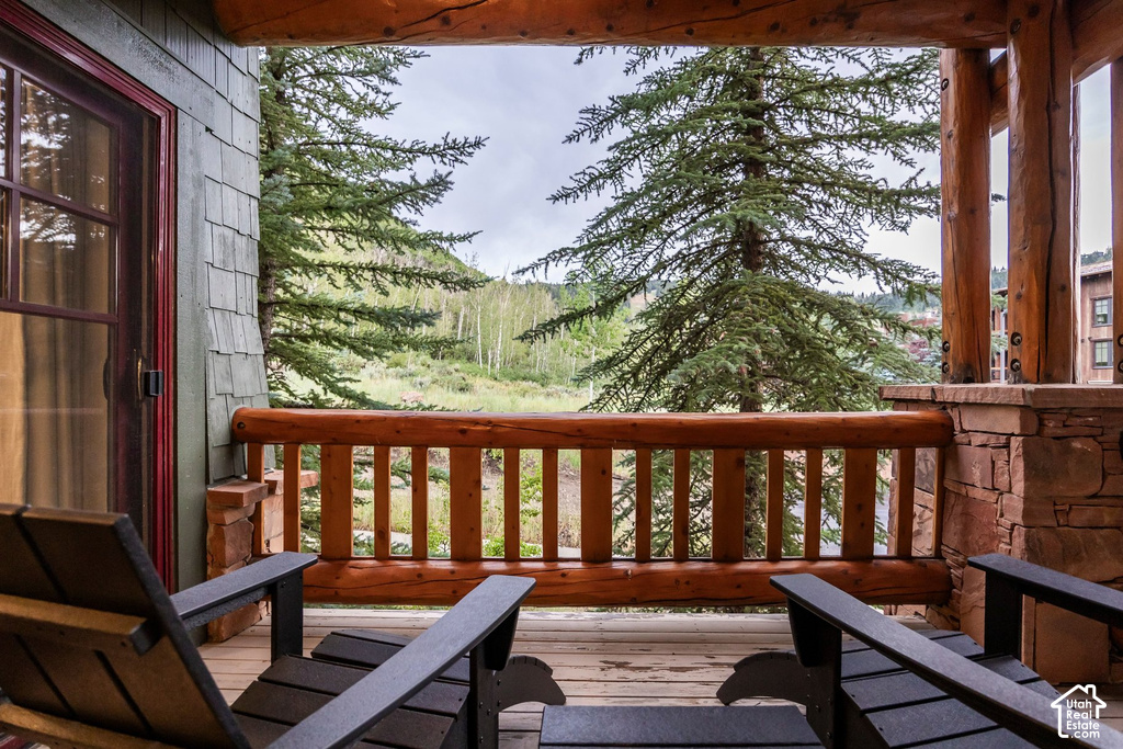 Covered outdoor deck with natural wood railing, log supports, and stone pillar accents