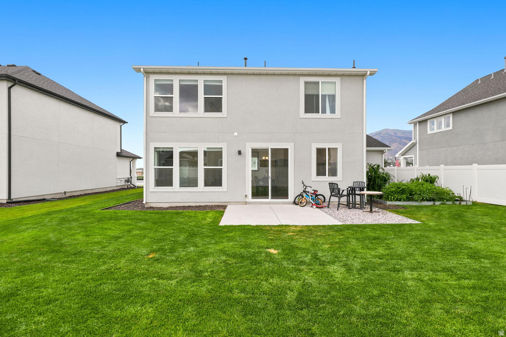 Spacious backyard featuring a concrete patio, expansive lawn, and a white privacy fence