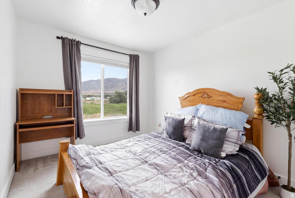 Bedroom with white walls, light-colored carpet flooring, and a single window with a mountain backdrop